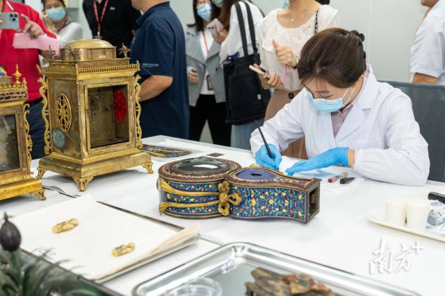 广东省博物馆无机组修复师秦臻正在对广钟进行珐琅修复。 