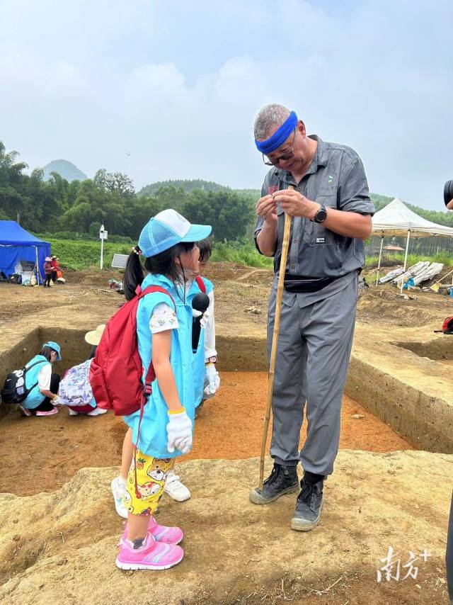 中山大学金志伟老师在教小朋友辨别发掘出的石头。