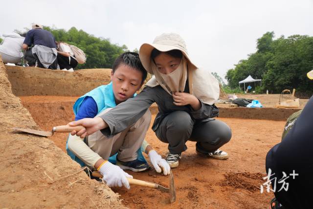 考古队员和中大学生教孩子们进行探方刮面。